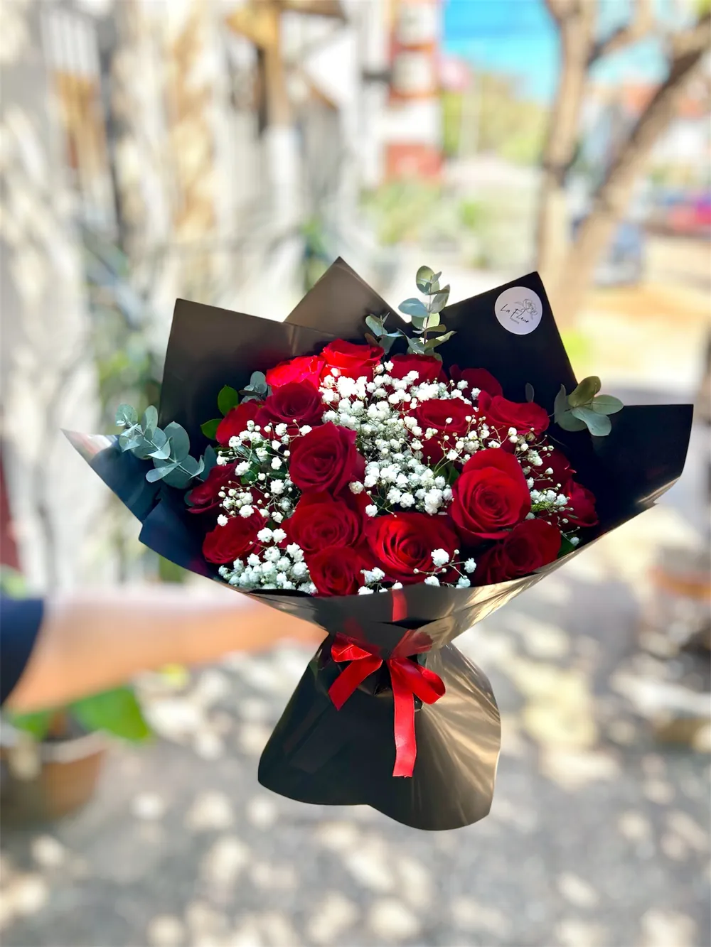 Ramo de rosas rojas con gipsófila en papel negro